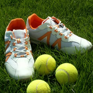 Tennisbälle und Tennisschuhe auf dem Rasen